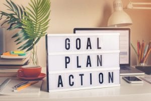 Goal plan action written on a board with fern behind